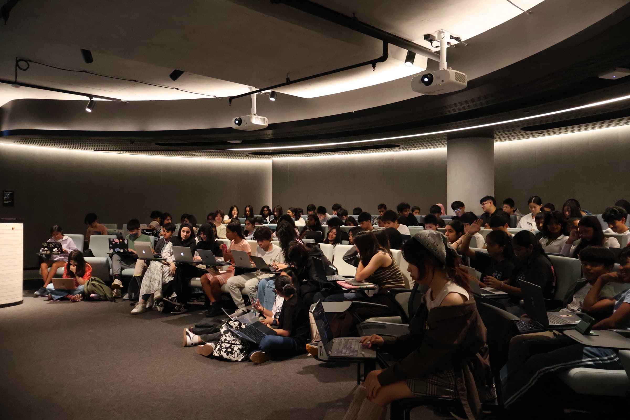 Teenagers collaborating on laptops at a hackathon-style event